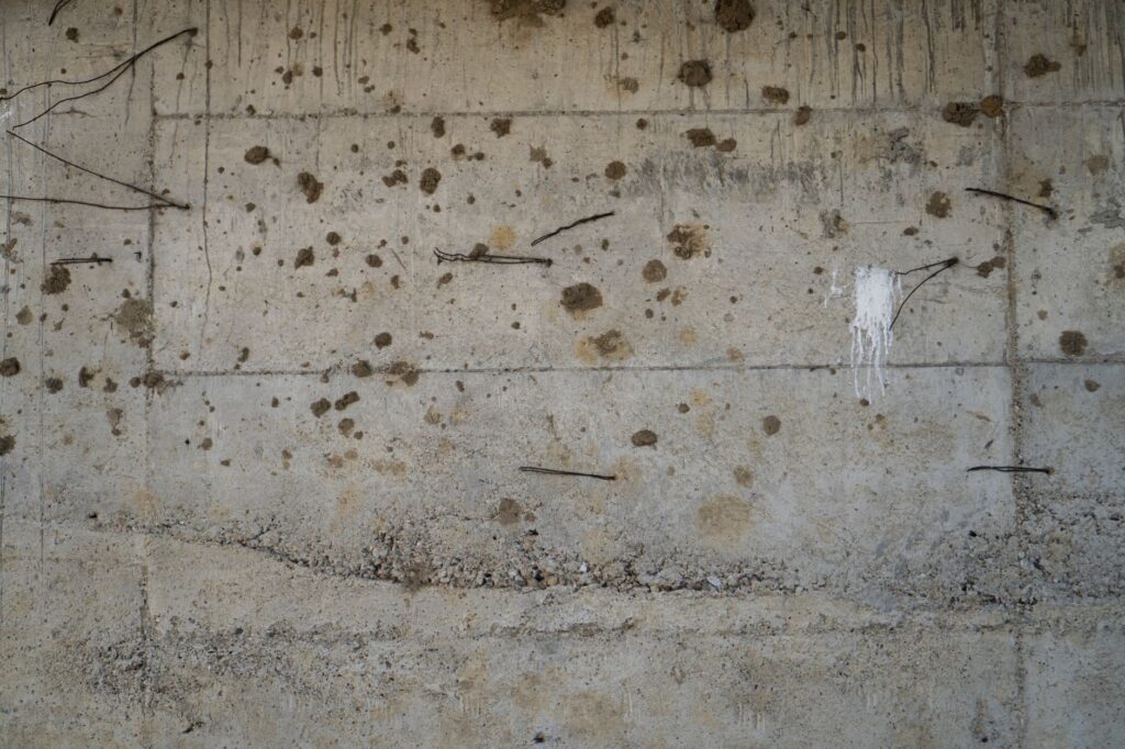 A detailed view of a weathered concrete wall with exposed rebar, showcasing industrial textures.